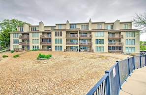 A multi-story residential building with balconies, a gravel courtyard, and a blue fence. - Lake Ozark Vacation Rental w/ Pool Access (Lake Ozark)