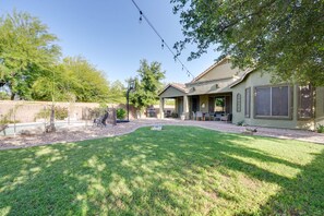 A residential backyard with a lawn, patio furniture, and a house with large windows and a covered porch. - 'sunny V' Arizona Retreat w/ Private Pool & Patio (Surprise)