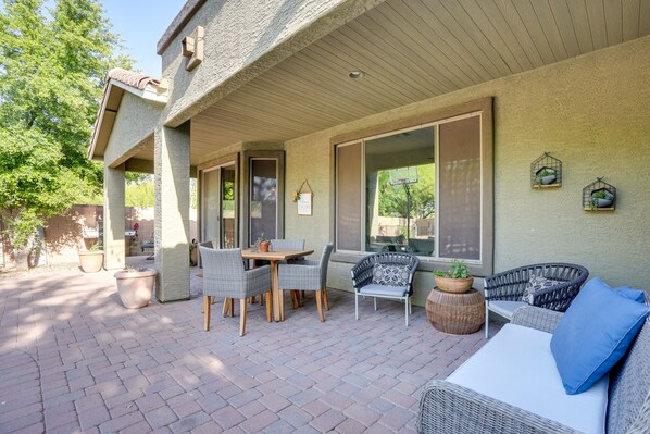 An outdoor patio with wicker furniture, potted plants, and a basketball hoop. - 'sunny V' Arizona Retreat w/ Private Pool & Patio (Surprise)