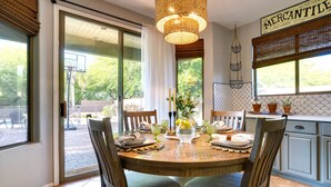 A dining area with a round wooden table, chairs, and a hanging light fixture. - 'sunny V' Arizona Retreat w/ Private Pool & Patio (Surprise)