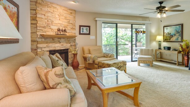 A living room with a stone fireplace, a glass coffee table, and a sofa with cushions.