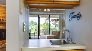 A kitchen with a sink, a wooden countertop, and a view of a balcony with a chair.