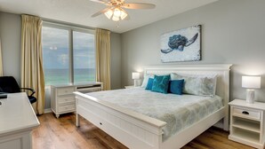 A bedroom with a bed, bedside tables, a desk, and a view of the ocean. - Fort Walton Beach Rental w/ Pool & Hot Tub Access (Fort Walton Beach)