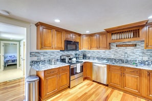 A kitchen with wooden cabinets, a granite countertop, a stainless steel stove, and a dishwasher. - Coastal Lincoln City Home w/ Spacious Deck! (Lincoln City)