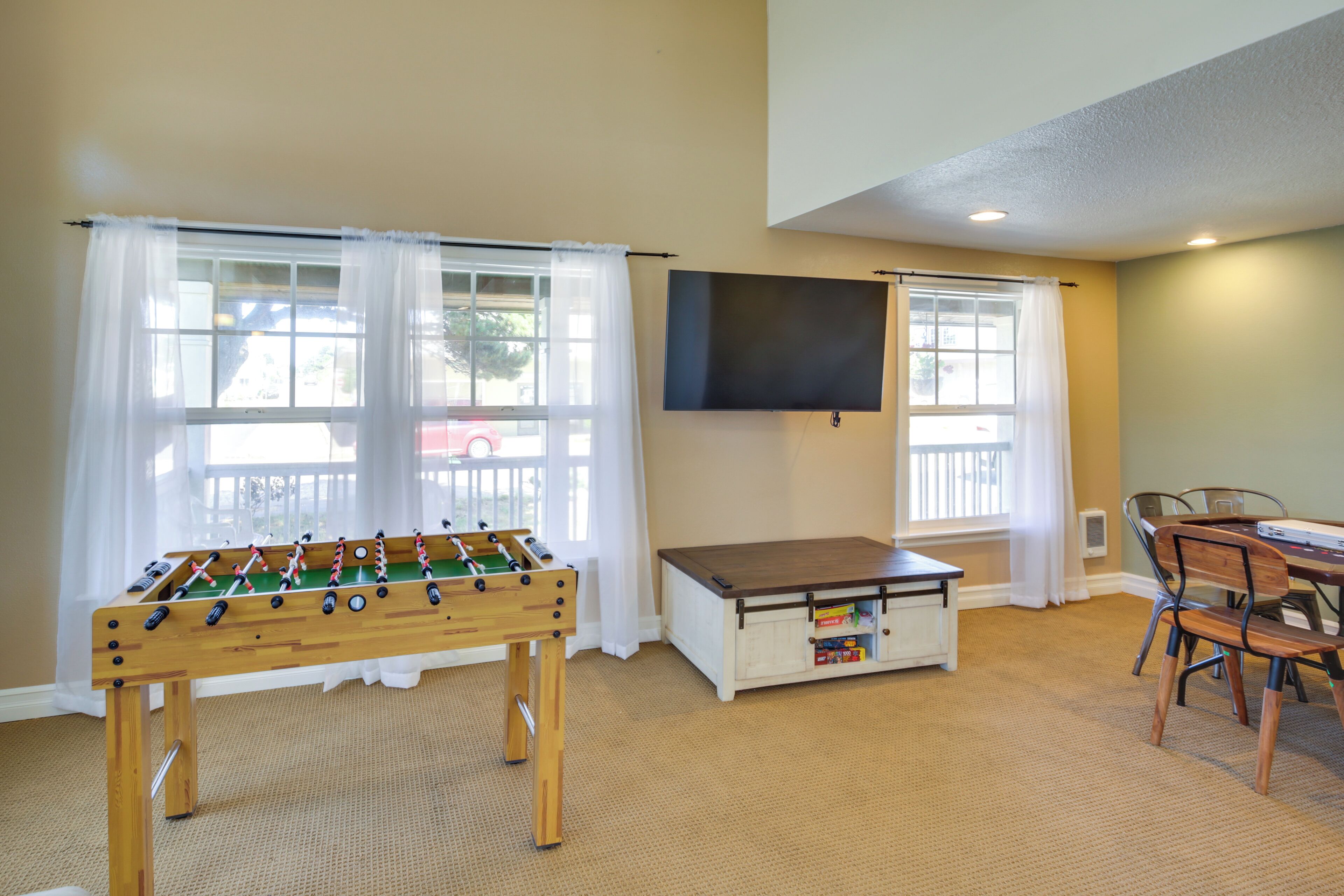 Ein Zimmer mit Tischfußball, einem an der Wand montierten Fernseher und einem Essbereich mit Stühlen und Tisch.