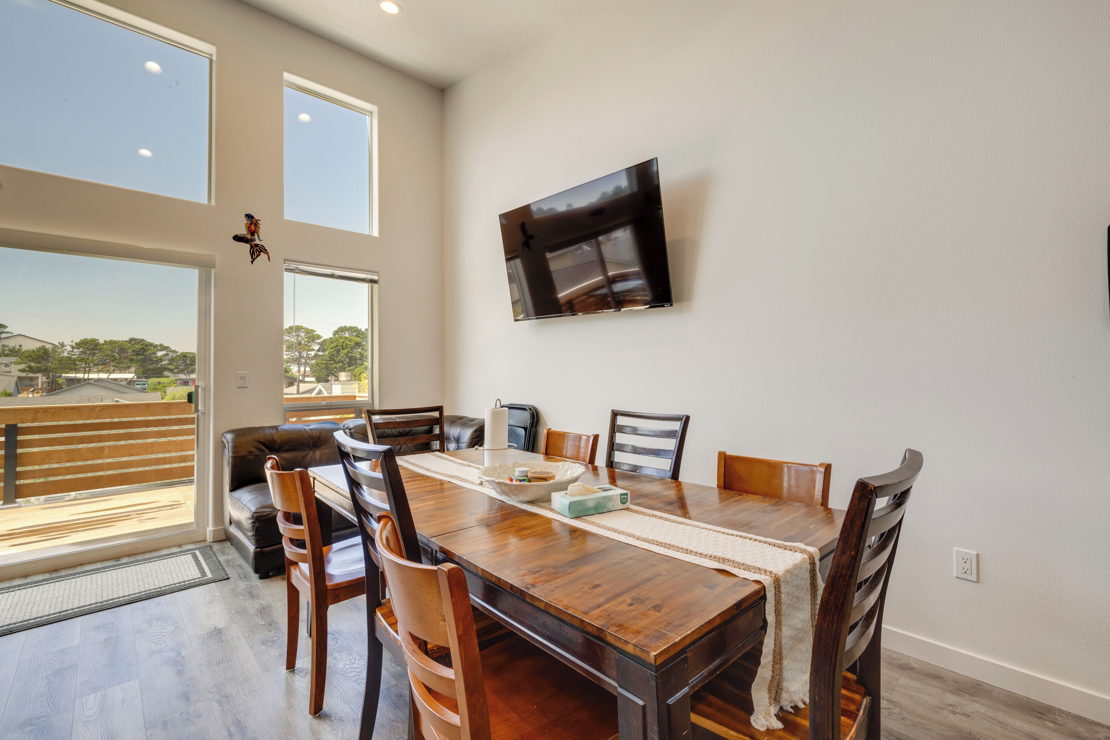 Un comedor con mesa de madera, sillas y un televisor montado en la pared.