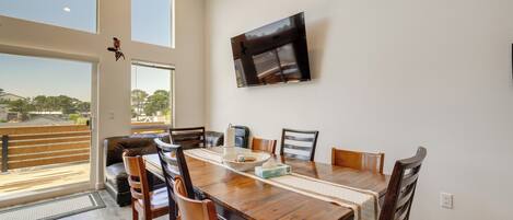 Un comedor con mesa de madera, sillas y un televisor montado en la pared.