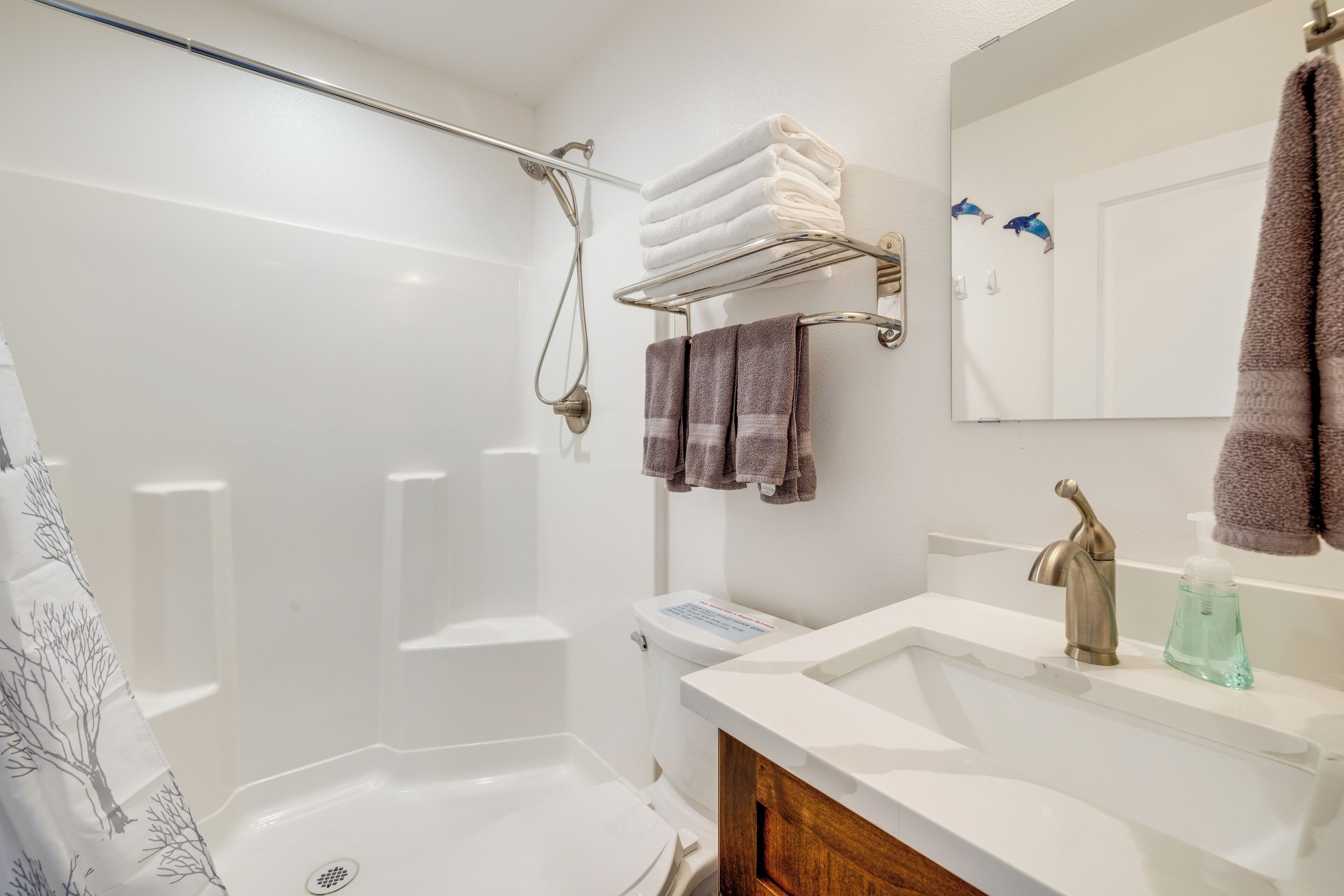 Un baño moderno con ducha acristalada, un lavabo blanco y un espejo con toallero.