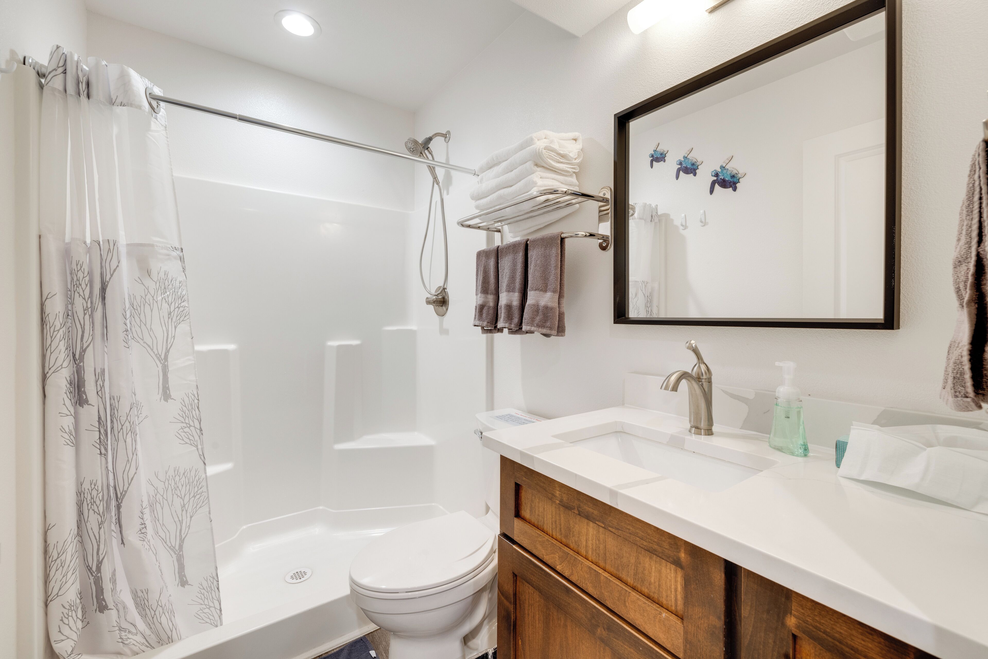 A modern bathroom with a shower, toilet, and vanity with a sink and mirror.