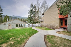 A building with a red entrance, a pathway leading to it, and a grassy area with trees. - Ski Retreat: Keystone Resort Condo w/ Heated Pool! (Keystone)
