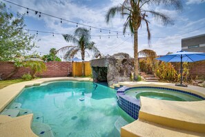 A swimming pool with a hot tub, surrounded by palm trees and a brick wall. - Luxe Yuma Home With Private Pool! (Yuma)