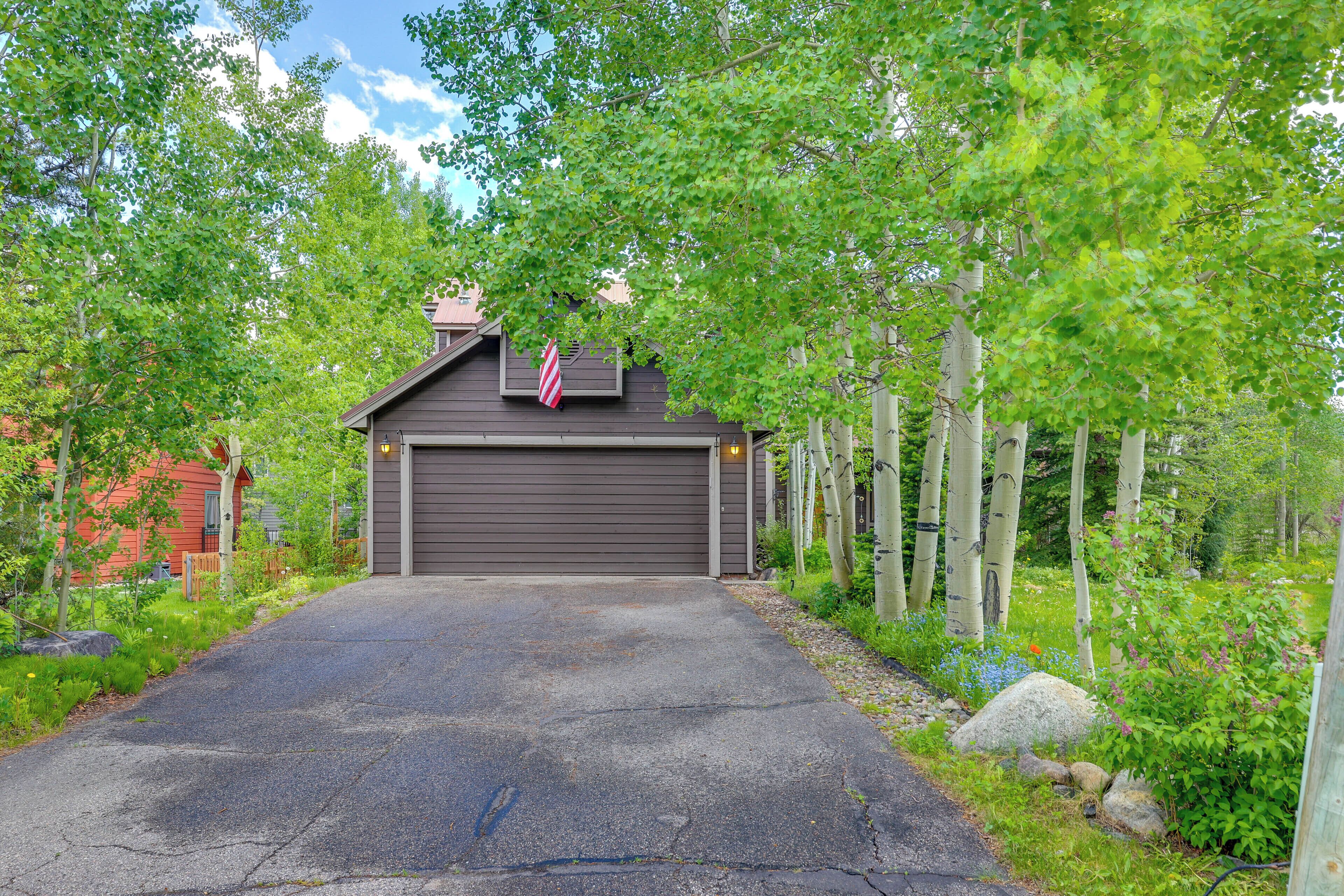 A garage with a red and white striped flag, surrounded by lush greenery and trees.