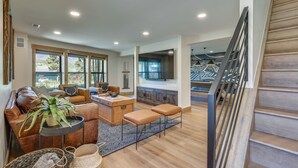 A spacious living area with a sofa, coffee table, and a dining table. There is a staircase leading to another level.