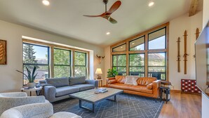 A spacious living room with a large window, a ceiling fan, and a fireplace.