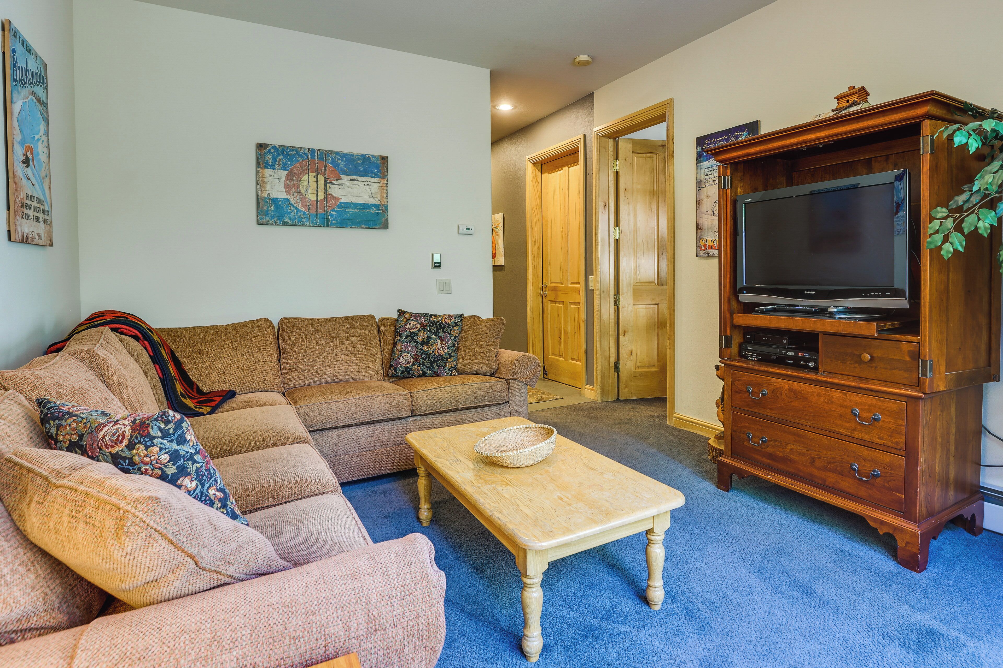 A living room with a sectional sofa, a coffee table, and a wooden cabinet with a television.