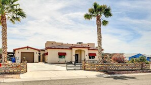 A two-story house with a garage, a stone wall, and a paved driveway. - Pet-friendly Vacation Rental Casita in Yuma (Yuma)