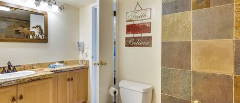 A bathroom with a sink, toilet, and shower area.