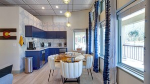 A modern kitchen with blue cabinets, a dining table with white chairs, and pendant lighting. - Keystone Lake Haven: Heated Pool & Ski Shuttle! (Keystone)