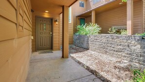 A covered entryway with a wooden door, a stone wall, and a small garden area.