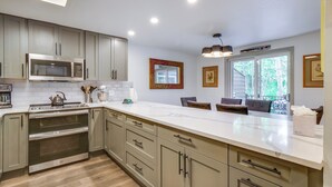 A modern kitchen with built-in appliances, a large island, and a view of the outdoors.