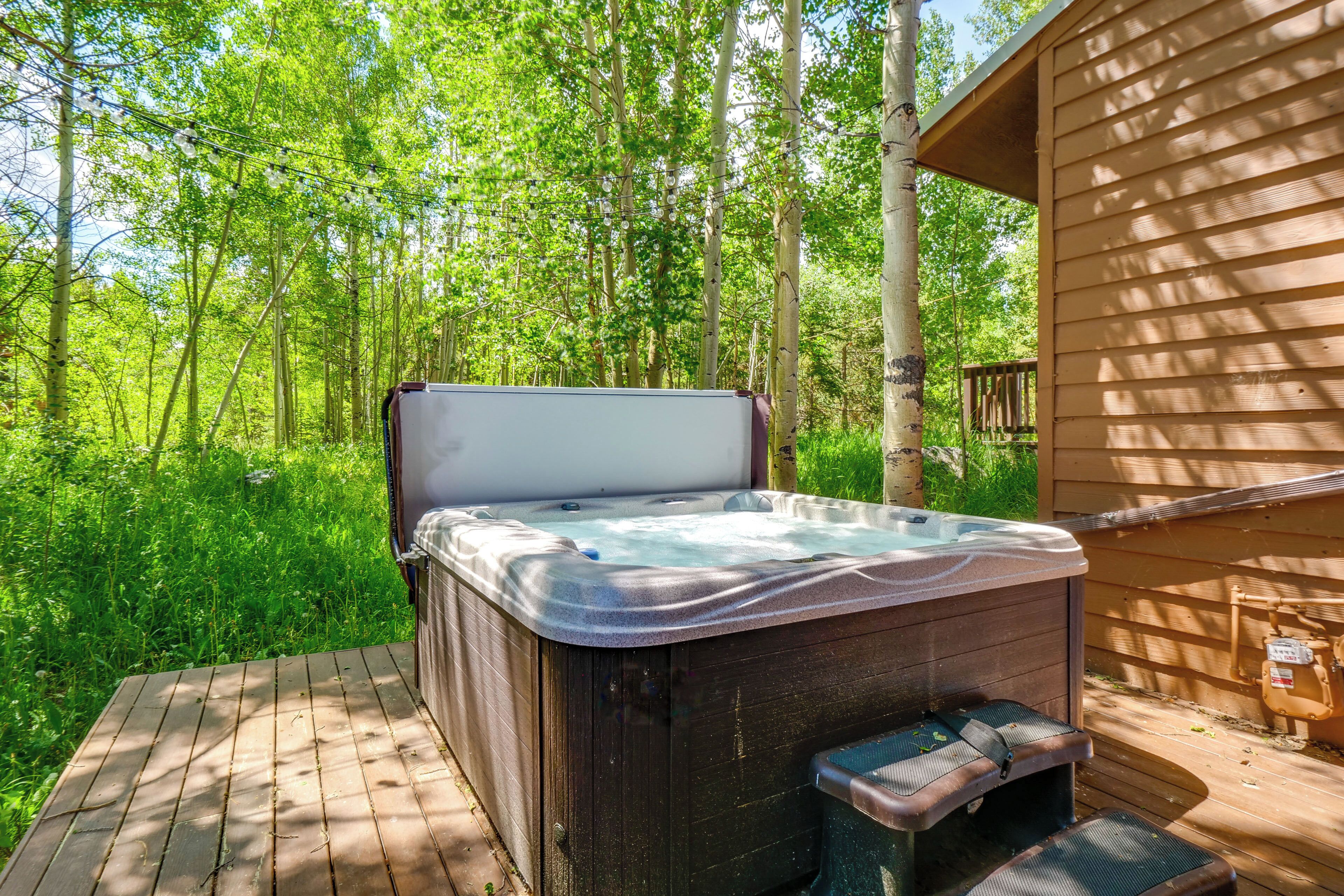Un bain à remous sur une terrasse en bois, entouré d’une végétation luxuriante.