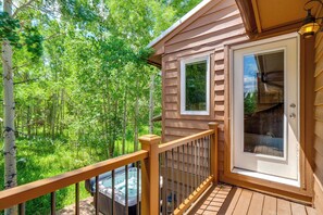 A wooden deck with a hot tub, a glass door, and a view of a forest. - Hot Tub & Deck: Family-friendly Frisco Townhome! (Frisco)