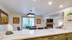 A modern kitchen with a large island, built-in appliances, and a dining area with chairs and a table.