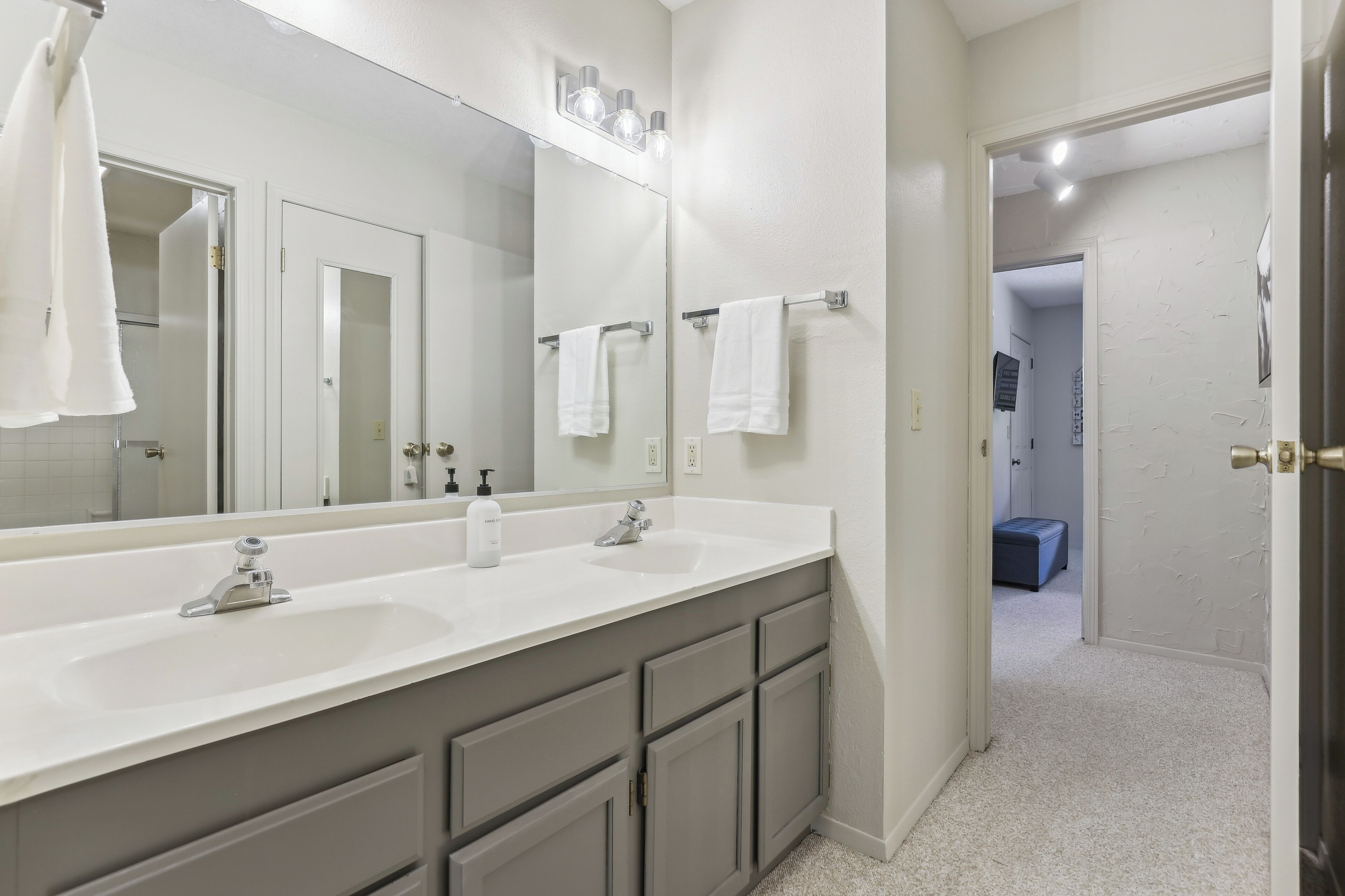 A bathroom with two sinks, a large mirror, and a towel rack.