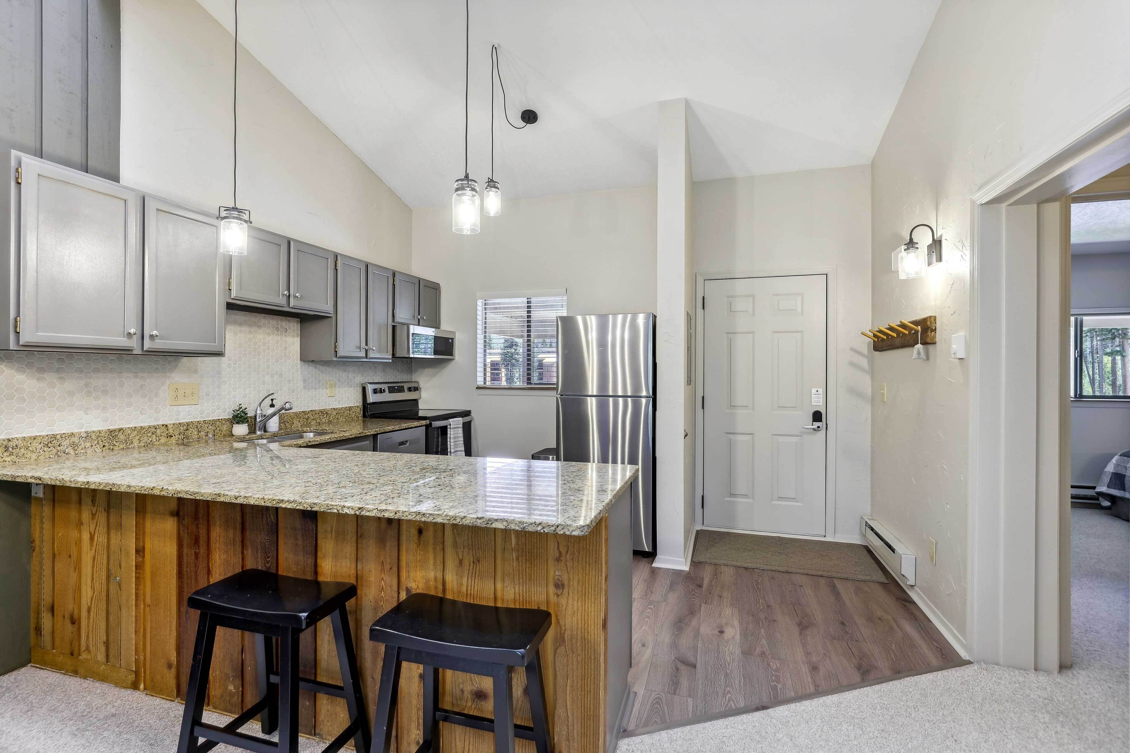 A modern kitchen with granite countertops, stainless steel appliances, and wooden accents.