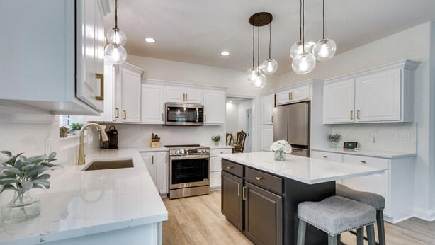 A modern kitchen with white cabinetry, stainless steel appliances, and a central island with bar stools. - Prime Peoria Retreat w/ Deck & Fireplace! (Peoria)