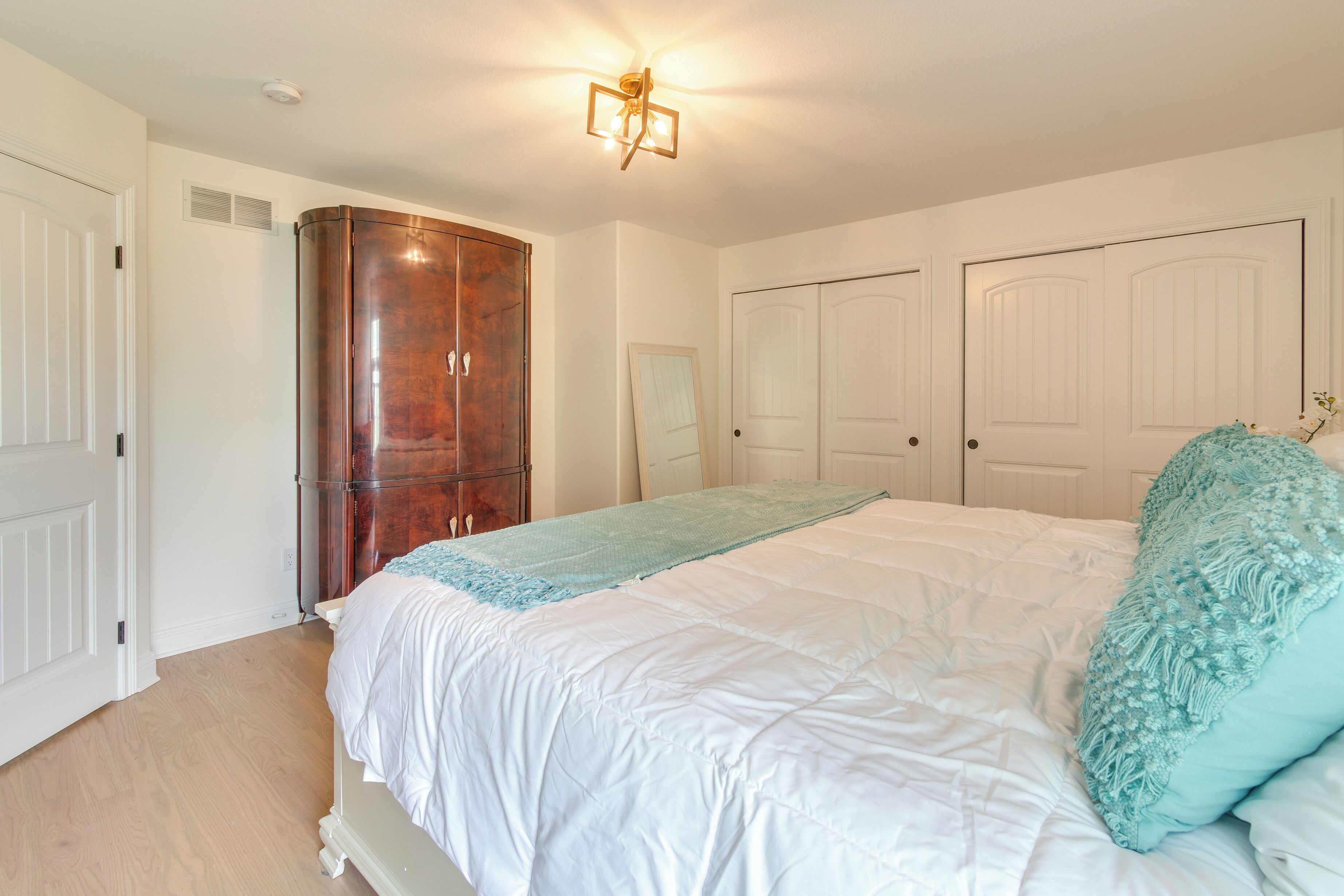 A bedroom with a large bed, a wardrobe, and two doors.