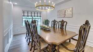 A dining room with a large wooden table, ornate chairs, a chandelier, and a window with blinds. - Prime Peoria Retreat w/ Deck & Fireplace! (Peoria)
