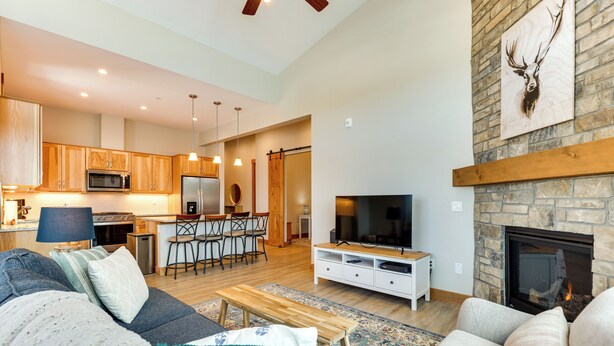 A spacious living area with a sofa, a television, and a fireplace. - Mountain-view Fraser Condo w/ Balcony + Hot Tub! (Fraser)