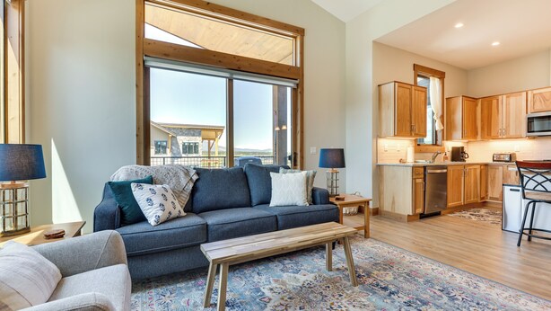 A modern living room with a sofa, a coffee table, and a view of the kitchen. - Mountain-view Fraser Condo w/ Balcony + Hot Tub! (Fraser)