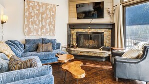A cozy living room with a fireplace, a large TV, and a view through a window. - 1 Mi to Keystone Resort: Mtn-view Family Escape! (Keystone)