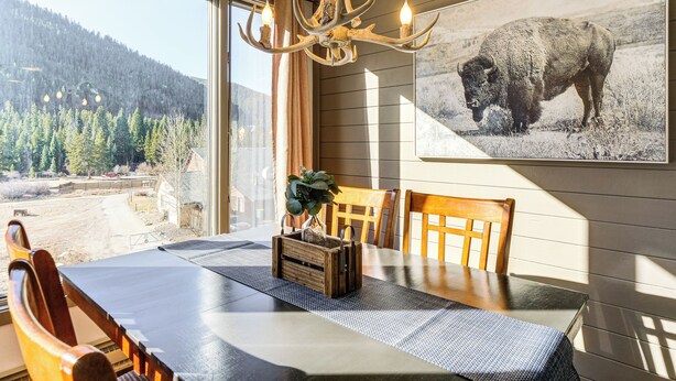 A dining area with a table, chairs, a chandelier, and a large buffalo picture on the wall. - 1 Mi to Keystone Resort: Mtn-view Family Escape! (Keystone)