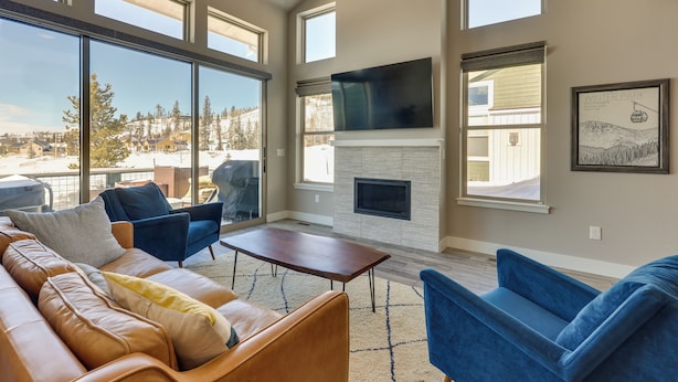 A spacious living room with a large window, a fireplace, and a television mounted on the wall. - Fraser Vacation Rental - Shuttle to Winter Park! (Fraser)