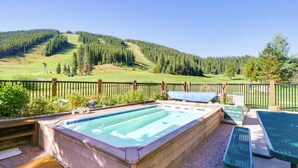 Ein Whirlpool mit Blick auf einen bewaldeten Hügel, ein Picknicktisch und eine umzäunte Terrassenfläche.
