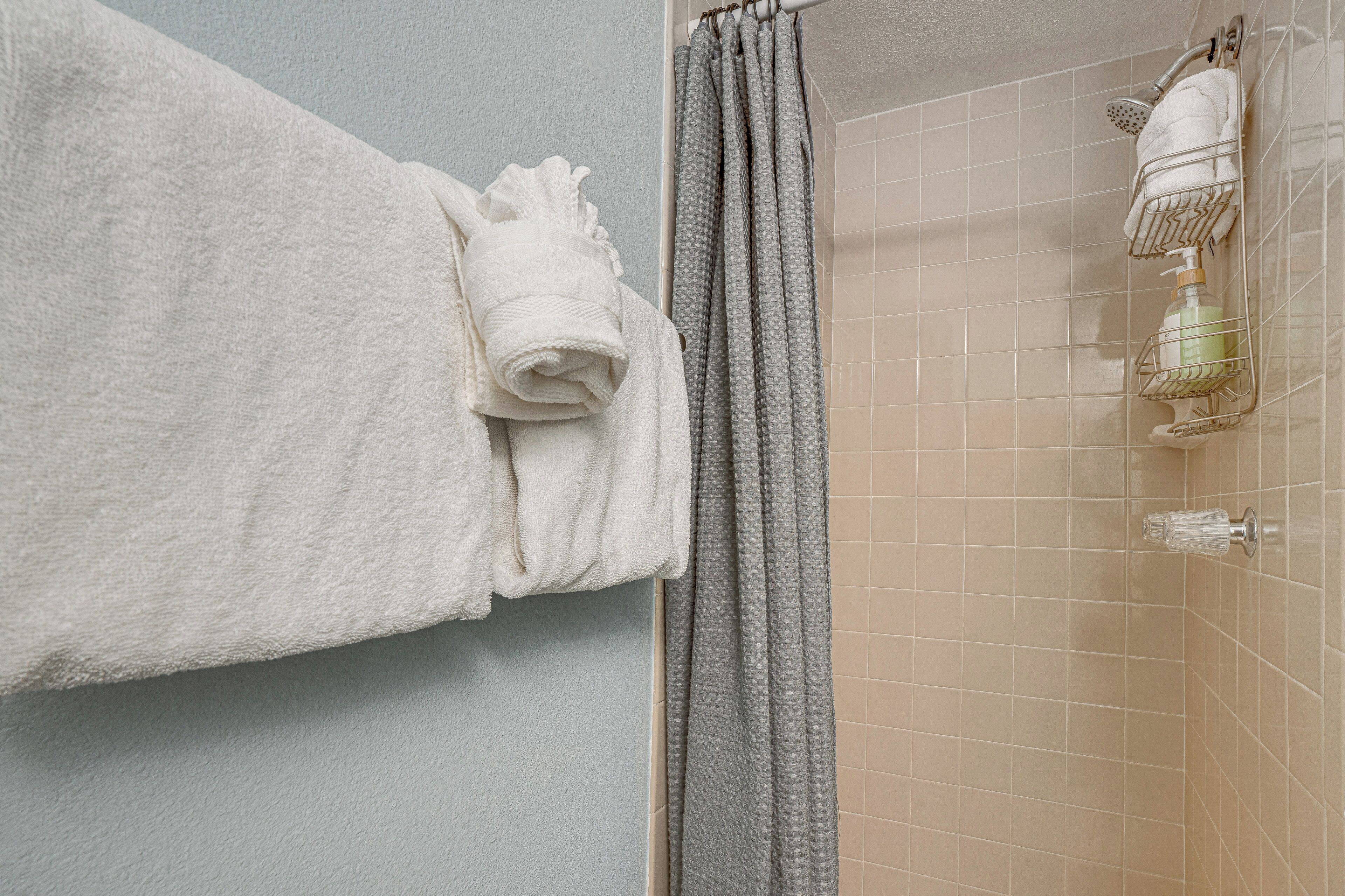 A bathroom with a towel rack holding a folded towel, a shower curtain, and a showerhead.