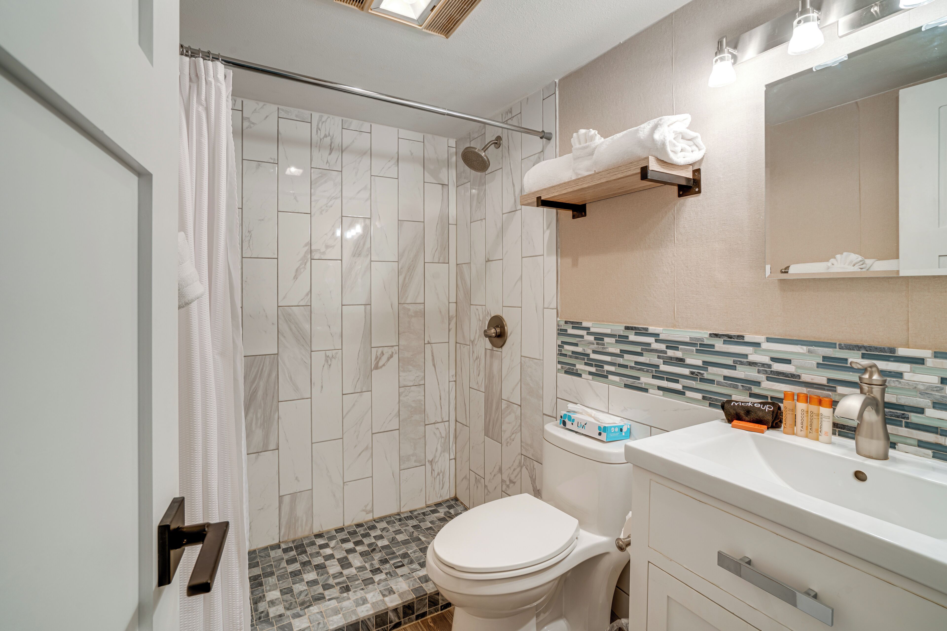A modern bathroom with a shower, toilet, and sink.