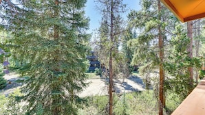 A view of a forested area with tall trees and a building in the background. - Winter Park Condo w/ Private Balcony: Near Skiing! (Winter Park)