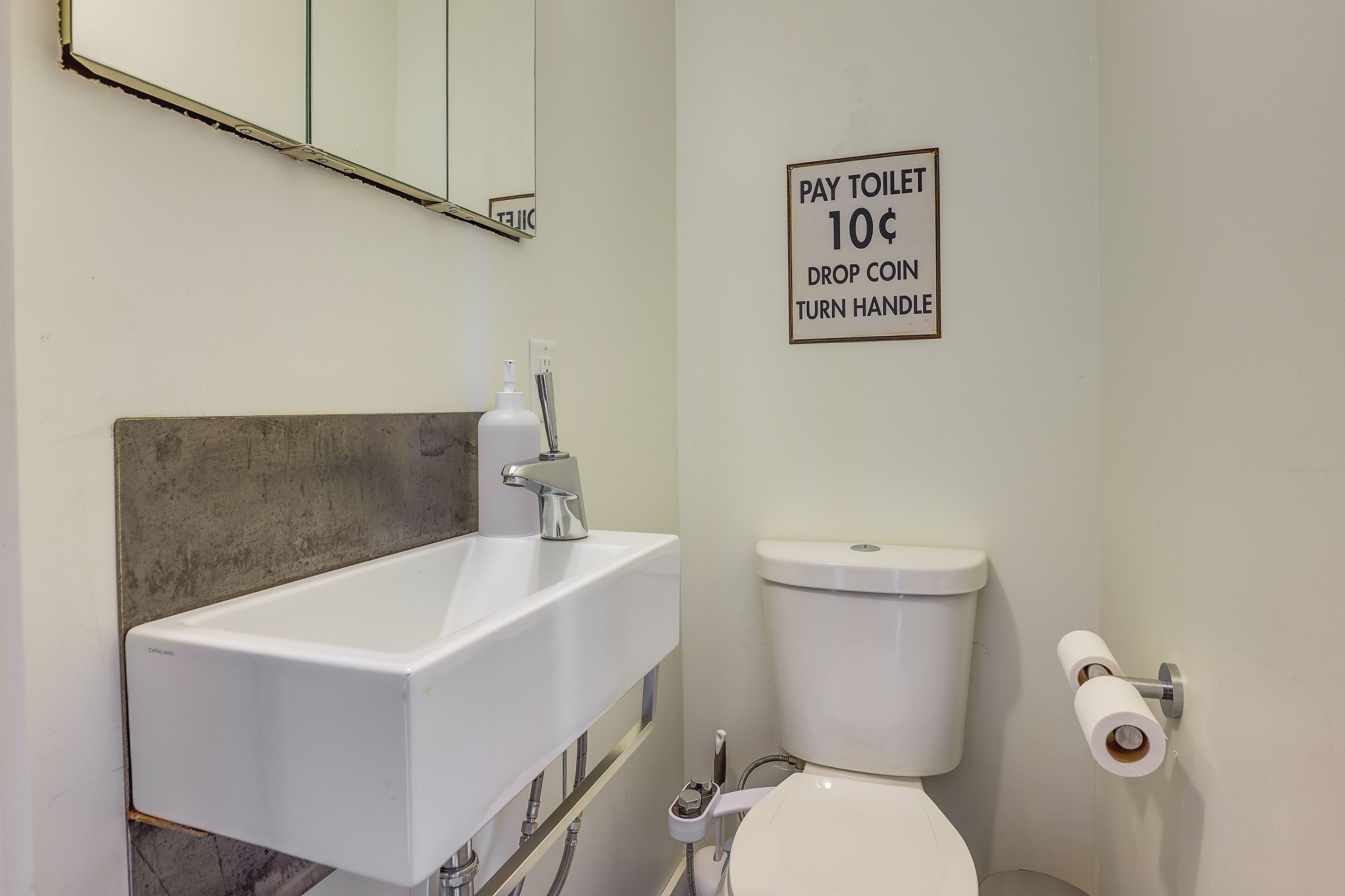 Ein Badezimmer mit Waschbecken, Toilette und einem Schild, das eine Gebühr von 10 Cent pro Toilettengang anzeigt.