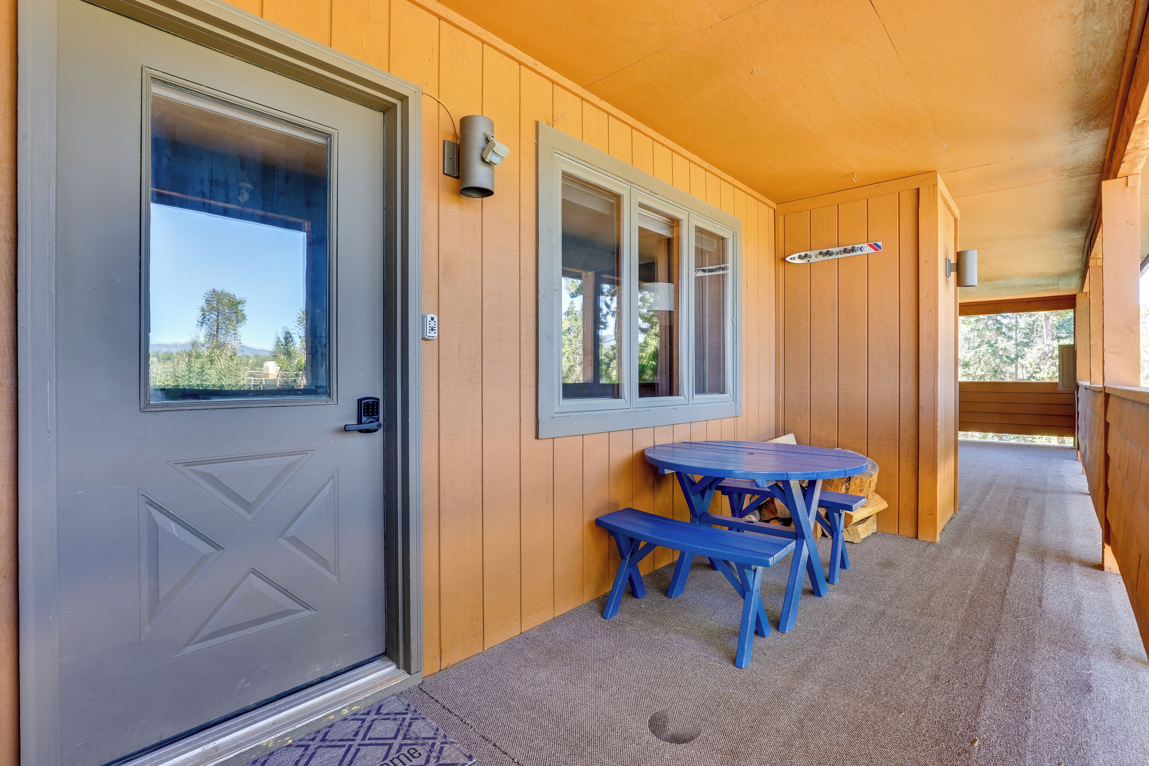 A covered porch with a gray door, wooden walls, and blue outdoor furniture.
