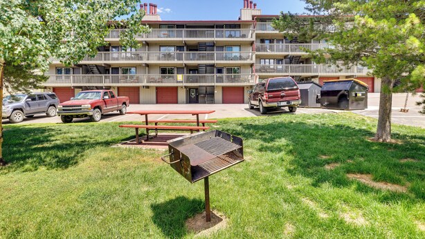 A multi-story building with a parking area, a barbecue grill, and a picnic table. - Fraser Condo Rental w/ Balcony, Mountain Views! (Fraser)