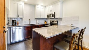 A modern kitchen with white cabinets, stainless steel appliances, and a marble island. - Fraser Condo Rental w/ Balcony, Mountain Views! (Fraser)