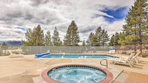 A hot tub surrounded by lounge chairs, a pool, and a fenced area with trees and mountains in the background. - Fraser Condo Rental w/ Balcony, Mountain Views! (Fraser)
