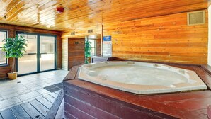 A wooden cabin interior with a hot tub, wooden floors, and a large window. - Winter Park Condo Rental: 4 Mi to Ski Resort! (Winter Park)