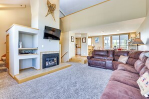 A spacious living room with a fireplace, a leather sofa, and a television mounted on the wall. - Winter Park Condo Rental: 4 Mi to Ski Resort! (Winter Park)