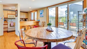A modern kitchen with wooden cabinets, a central island, and a dining area with a round table and chairs. - Winter Park Condo Rental: 4 Mi to Ski Resort! (Winter Park)
