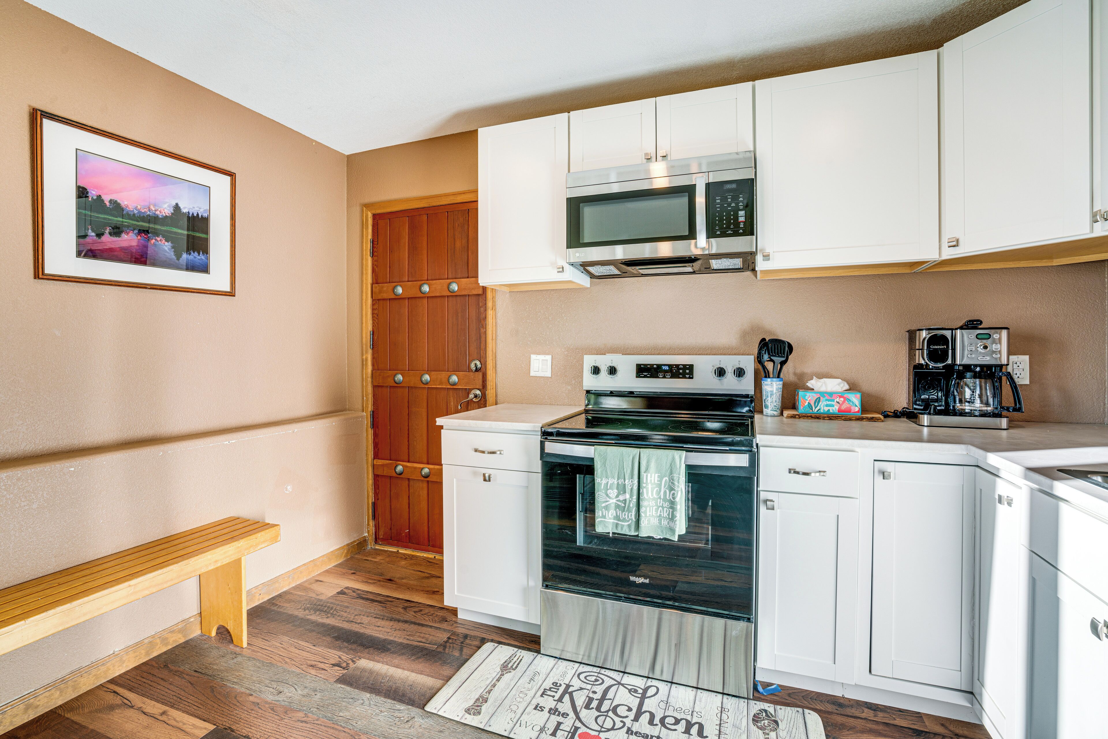 A compact kitchen with white cabinets, a microwave, an oven, and a coffee maker.